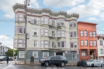 San Francisco apartment for rent - A street view of a multi-story building with a car parked in front.