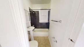 San Francisco apartment for rent - A white toilet is in a small bathroom with a black tile shower.