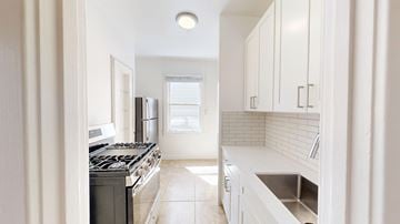 San Francisco apartment for rent - A kitchen with white cabinets and a black stove top oven.
