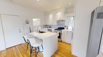 San Francisco apartment for rent - A kitchen with white cabinets and a white island with a black chair.