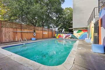 Berkeley apartment for rent - a swimming pool is next to a building with a fence and a mural