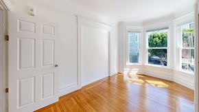San Francisco apartment for rent - A room with a white door and a window with a view of trees and buildings outside.