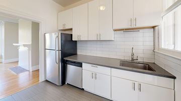 San Francisco apartment for rent - A kitchen with white cabinets and a black countertop.