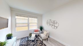 San Francisco apartment for rent - A living room with a white sofa, a black and white rug, a red cushion, a white chair, a potted plant, and a wall art.