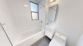 San Francisco apartment for rent - A white bathroom with a tub, sink, and mirror.
