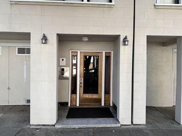 San Francisco apartment for rent - A white building with a black mat in front of a wooden door.