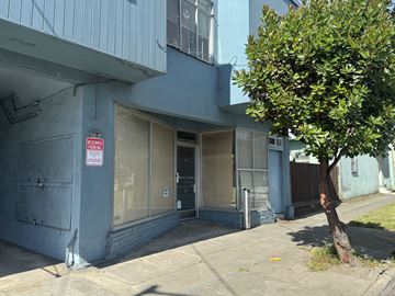 San Francisco apartment for rent - A tree is in front of a grey building with a sign on it.