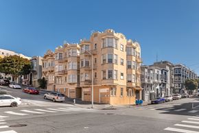 San Francisco apartment for rent - A street view of a residential building with cars parked on the side of the road.