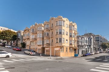 San Francisco apartment for rent - A street view of a residential building with cars parked on the side of the road.