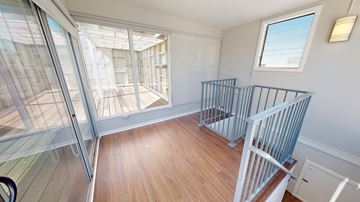 San Francisco apartment for rent - A room with a wooden floor and a glass wall leading to a balcony.
