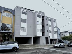 San Francisco apartment for rent - A white car is parked in front of a grey and yellow apartment building.