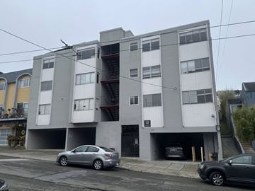 San Francisco apartment for rent - A grey and white apartment building with cars parked in front.
