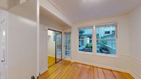 San Francisco apartment for rent - A room with a wooden floor and a window showing a view of a house.