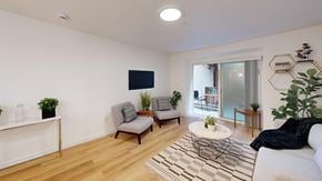 San Francisco apartment for rent - A living room with a white couch, a grey armchair, a white coffee table, and a black and white rug.
