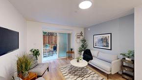 San Francisco apartment for rent - A living room with a white couch, a coffee table, and a TV on the wall.