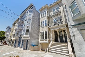 San Francisco apartment for rent - A row of three-story houses with white and grey facades and staircases leading to the doors.