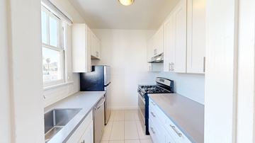 San Francisco apartment for rent - A kitchen with white cabinets and a black fridge.