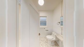 Berkeley apartment for rent - A white bathroom with a toilet, sink, and window.
