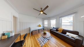 Berkeley apartment for rent - A living room with a brown couch, a coffee table, and a ceiling fan.