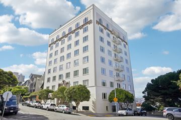 San Francisco apartment for rent - A white building with many windows is on a street with cars parked in front.