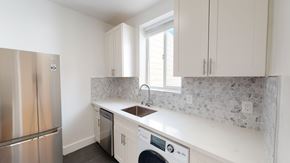 San Francisco apartment for rent - A kitchen with a stainless steel refrigerator, a washer and dryer, and white cabinets.
