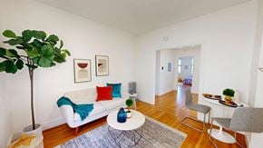 San Francisco apartment for rent - A living room with a white couch, a blue throw, a white coffee table, and a green plant.