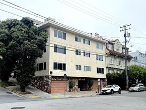 San Francisco apartment for rent - A two-story building with a garage door is situated on a street with cars parked in front.