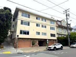 San Francisco apartment for rent - A white building with a garage door is situated on a street corner.