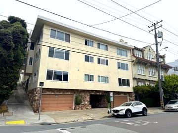 San Francisco apartment for rent - A white building with a garage door is situated on a street corner.