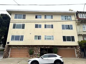 San Francisco apartment for rent - A white car is parked in front of a tan building.