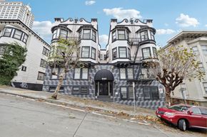 San Francisco apartment for rent - A red car is parked on the sidewalk in front of a building with a black awning.