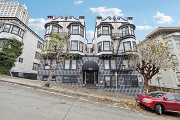 San Francisco apartment for rent - A red car is parked on the sidewalk in front of a building with a black awning.