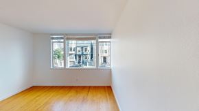 San Francisco apartment for rent - A room with wooden floors and a window showing a view of a building.