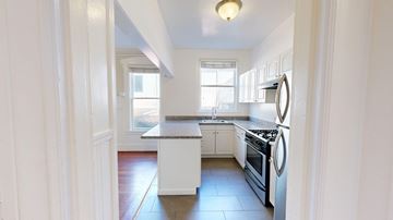 San Francisco apartment for rent - A kitchen with white cabinets and a stove top oven.