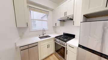 San Francisco apartment for rent - A kitchen with white cabinets and a black stove top oven.