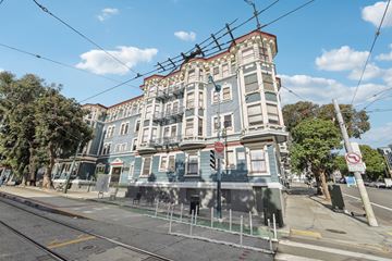 San Francisco apartment for rent - A street view of a building with a blue and white facade and a red roof.
