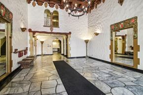San Francisco apartment for rent - Grand hallway with a high ceiling and a chandelier hanging from the center, a wooden bench and a mirror