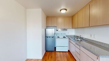 San Francisco apartment for rent - A kitchen with a white fridge, white stove, and wooden cabinets.