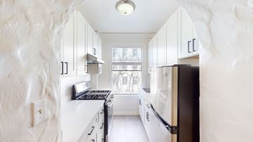 San Francisco apartment for rent - A kitchen with white cabinets and black appliances.