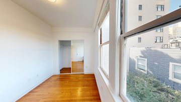 San Francisco apartment for rent - A room with a wooden floor and a large window overlooking a street.
