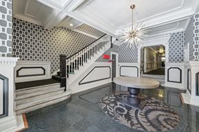 San Francisco apartment for rent - Elegant foyer with patterned wallpaper, a modern chandelier, unique round table, and decorative area rug, leading to a staircase