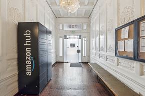 San Francisco apartment for rent - Ornate hallway with Amazon Hub locker, chandelier, bulletin board, wooden bench, and glass door
