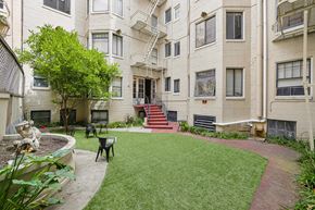 San Francisco apartment for rent - Courtyard with a fence, covered in lush green grass, and a brick walkway leads up to the entrance of the building