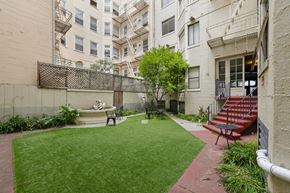 San Francisco apartment for rent - Courtyard with a wooden fence, with a small garden featuring a fountain and a statue, and a staircase that leads up the the entrance of the apartment building