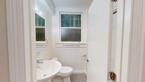 San Francisco apartment for rent - A white bathroom with a toilet, sink, and window.