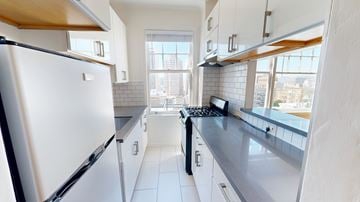 San Francisco apartment for rent - A white refrigerator is in a kitchen with white cabinets and a black stove.