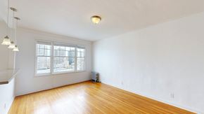 San Francisco apartment for rent - A room with wooden floors and a window overlooking a cityscape.