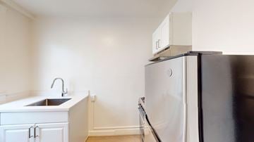 San Francisco apartment for rent - A black refrigerator sits in a kitchen next to a sink.