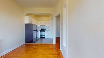 San Francisco apartment for rent - A kitchen with a refrigerator, oven, and sink is visible through a doorway.