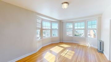 San Francisco apartment for rent - A sunny room with wooden floors and large windows.